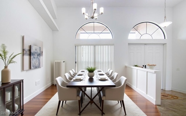 dining space with radiator heating unit, beverage cooler, dark hardwood / wood-style floors, a towering ceiling, and a chandelier