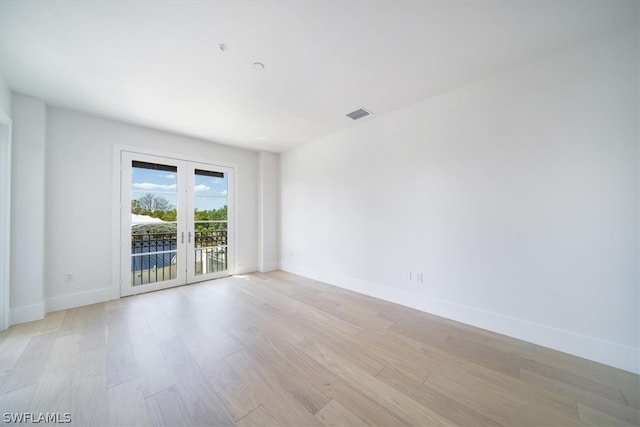 empty room with light hardwood / wood-style floors and french doors