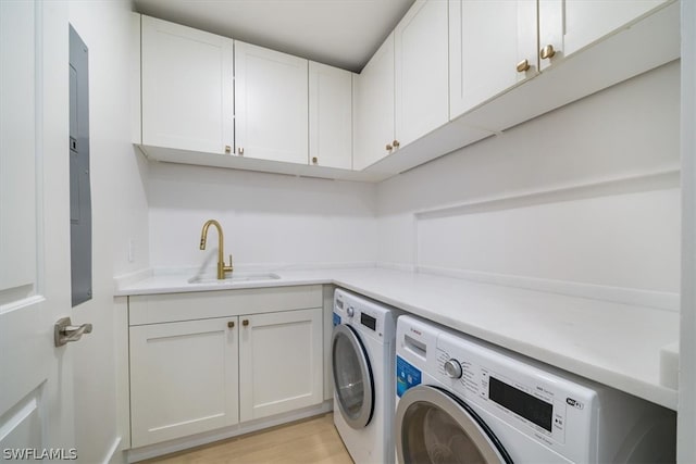 laundry room with sink, light hardwood / wood-style flooring, independent washer and dryer, and cabinets