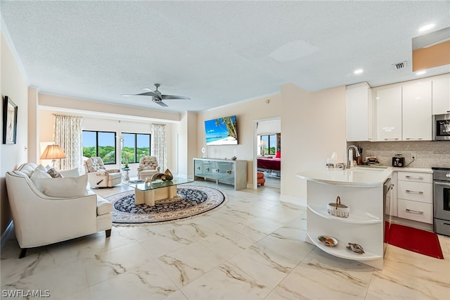 living room featuring ceiling fan, sink, and a textured ceiling