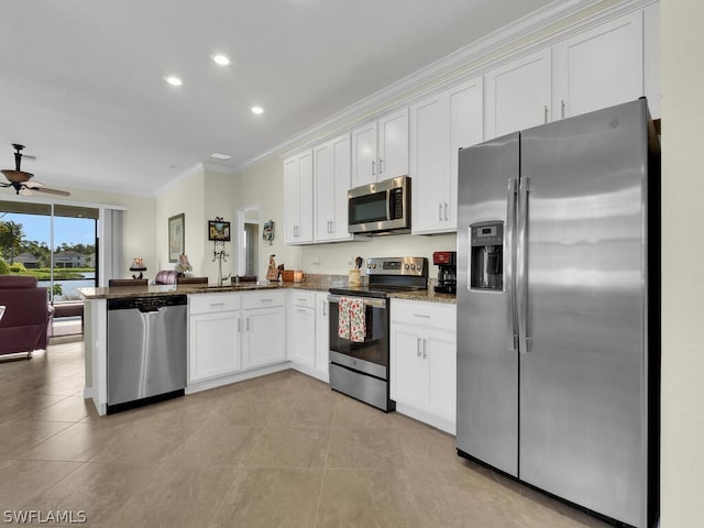 kitchen with crown molding, appliances with stainless steel finishes, dark stone countertops, white cabinets, and kitchen peninsula