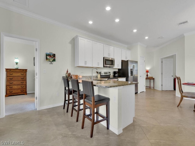 kitchen with stone countertops, white cabinetry, a kitchen breakfast bar, kitchen peninsula, and stainless steel appliances