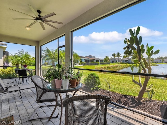 sunroom featuring ceiling fan and a water view