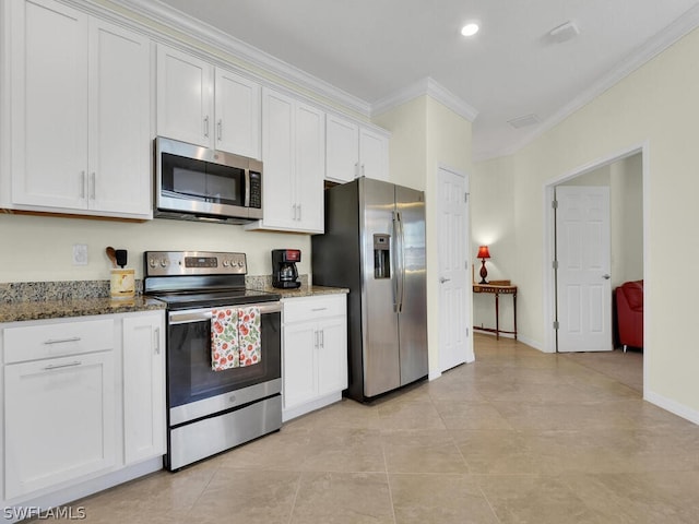 kitchen with white cabinetry, dark stone countertops, stainless steel appliances, ornamental molding, and light tile patterned flooring