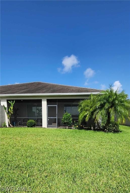 rear view of house with a sunroom and a lawn