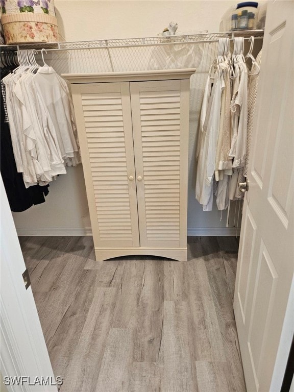 walk in closet with light hardwood / wood-style flooring