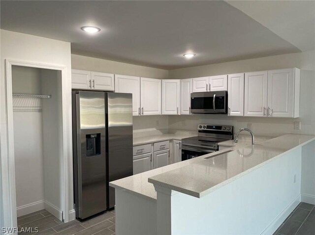 kitchen with kitchen peninsula, stainless steel appliances, and white cabinetry