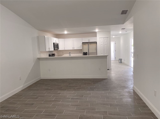 kitchen featuring sink, stainless steel appliances, kitchen peninsula, and white cabinets