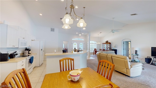 dining room featuring ceiling fan with notable chandelier, light carpet, and high vaulted ceiling