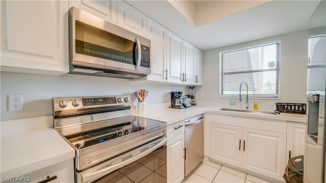 kitchen with sink, white cabinets, light tile floors, and stainless steel appliances