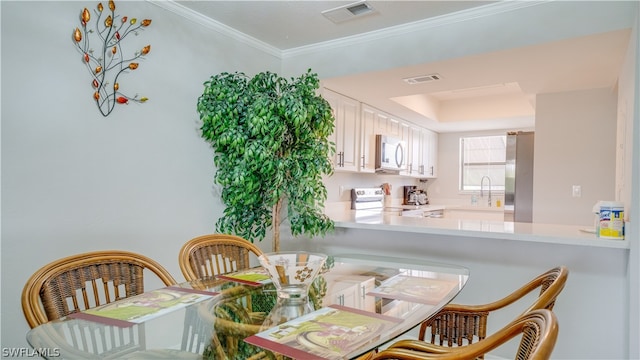 dining area featuring sink, a tray ceiling, and crown molding