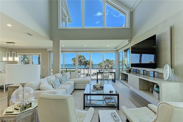 living room with hardwood / wood-style floors, a water view, and a towering ceiling