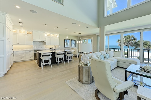 living room featuring light hardwood / wood-style flooring, a water view, and a wealth of natural light