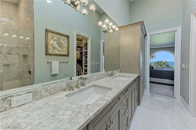 bathroom featuring tile flooring, vanity with extensive cabinet space, dual sinks, a notable chandelier, and a tile shower