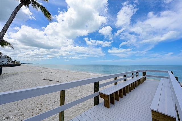 view of dock featuring a beach view and a water view