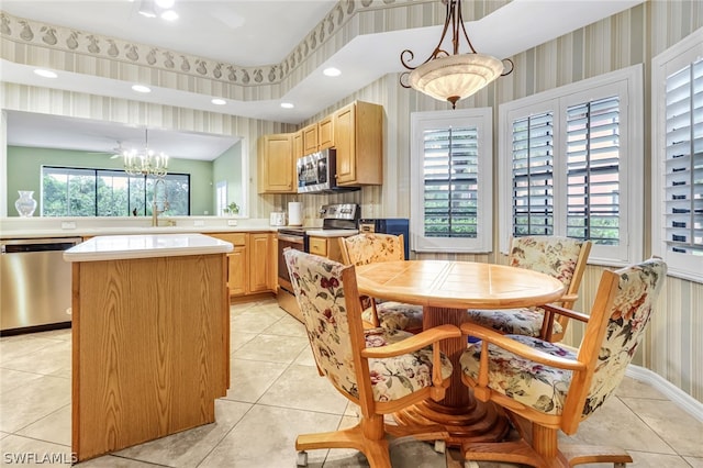 kitchen featuring light tile patterned floors, stainless steel appliances, a kitchen island, and hanging light fixtures