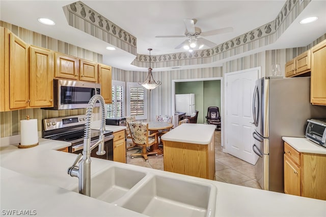 kitchen with stainless steel appliances, ceiling fan, sink, a center island, and hanging light fixtures