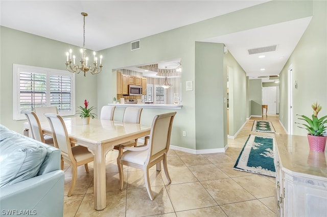 dining space with light tile patterned floors and an inviting chandelier