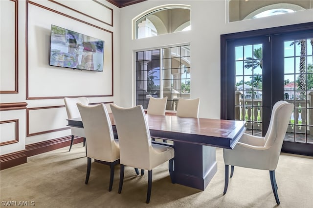 dining space featuring carpet flooring, crown molding, and a high ceiling