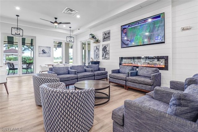 living room with ceiling fan with notable chandelier and light wood-type flooring