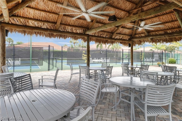 patio terrace at dusk featuring a gazebo, tennis court, and ceiling fan