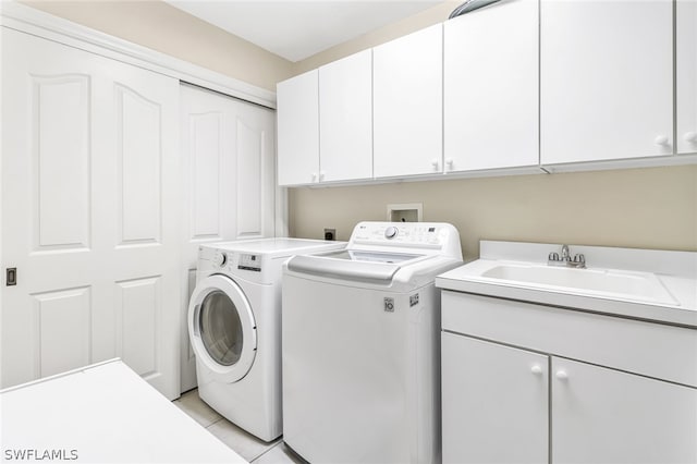 clothes washing area featuring separate washer and dryer, sink, light tile patterned floors, and cabinets