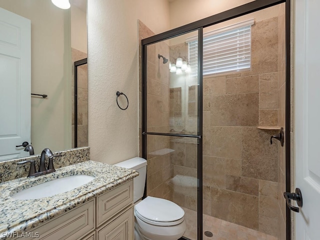 bathroom featuring vanity, toilet, and a shower with shower door