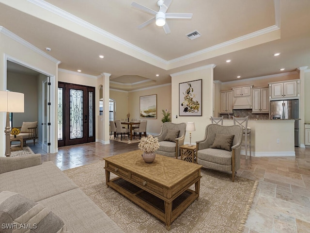 living room featuring ceiling fan, a raised ceiling, and ornamental molding