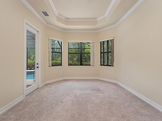 carpeted empty room with ornamental molding and a tray ceiling