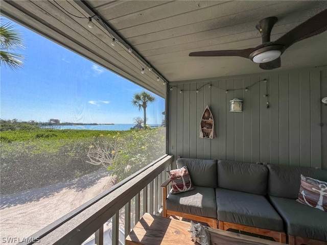 balcony featuring an outdoor living space, ceiling fan, and a water view