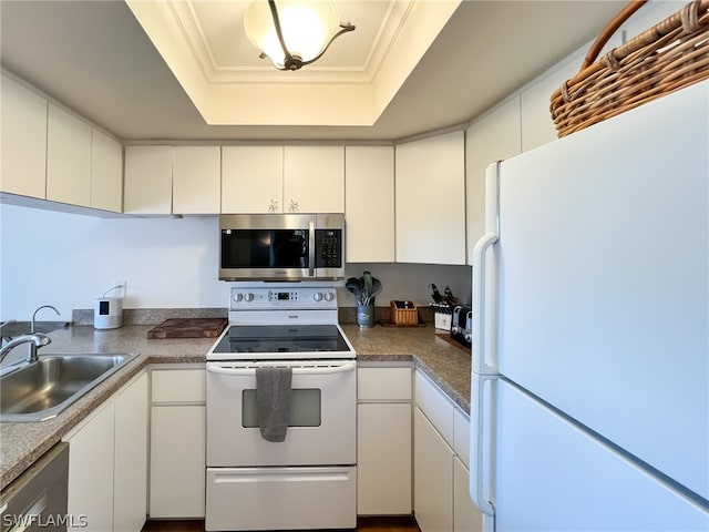 kitchen featuring appliances with stainless steel finishes, white cabinetry, sink, and a tray ceiling