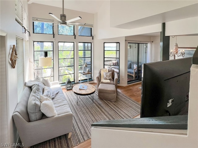 living room featuring ceiling fan, light hardwood / wood-style floors, and a high ceiling