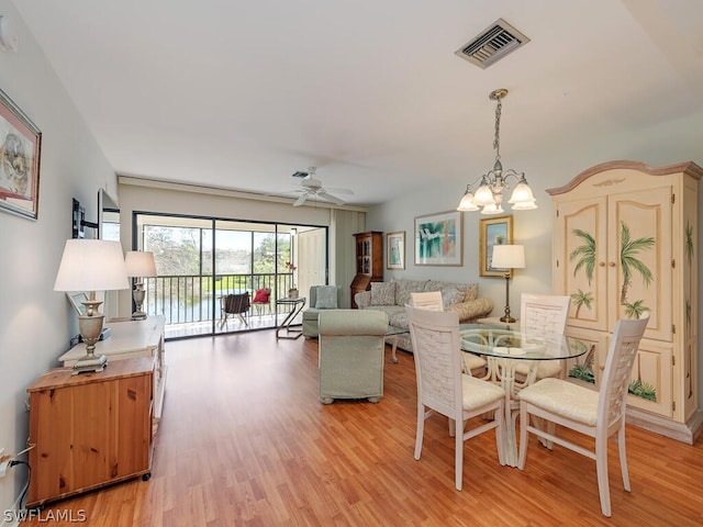 dining room with ceiling fan with notable chandelier and light hardwood / wood-style floors