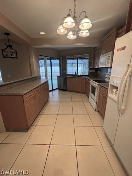 kitchen featuring light tile floors, sink, white appliances, decorative light fixtures, and an inviting chandelier