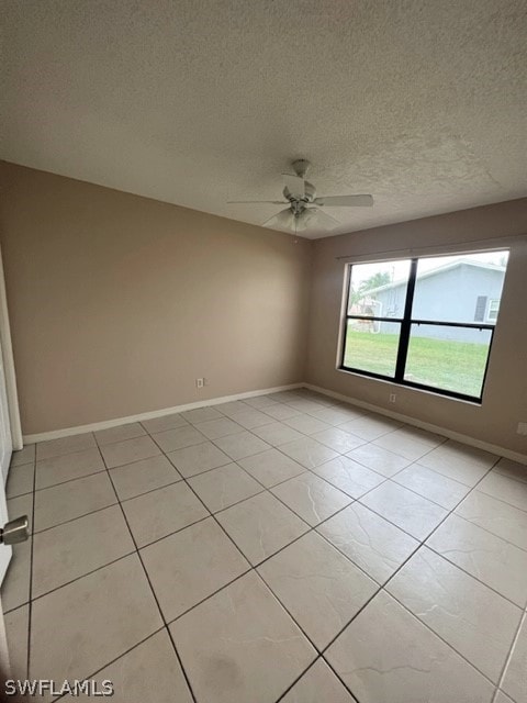 tiled empty room featuring ceiling fan and a textured ceiling