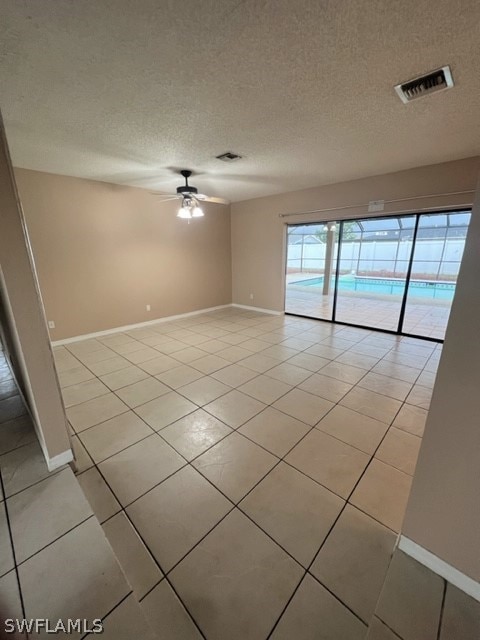 unfurnished room featuring ceiling fan, light tile floors, and a textured ceiling