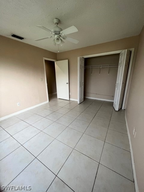 unfurnished bedroom featuring a closet, a textured ceiling, ceiling fan, and light tile flooring