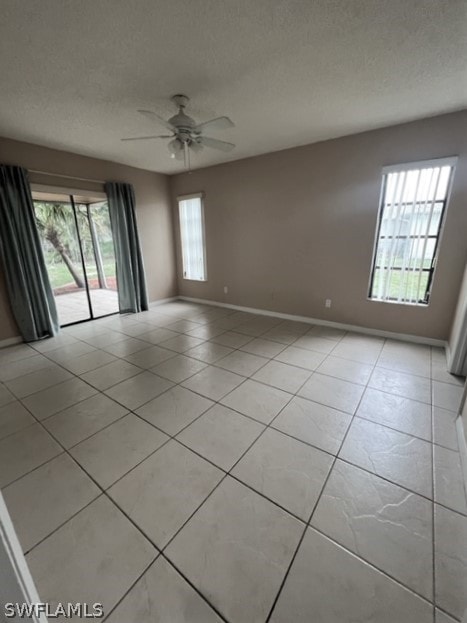 tiled spare room featuring plenty of natural light and ceiling fan