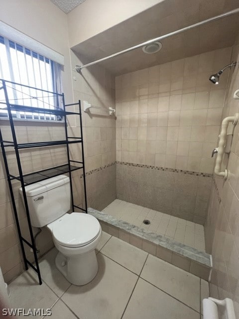 bathroom featuring tiled shower, toilet, and tile flooring