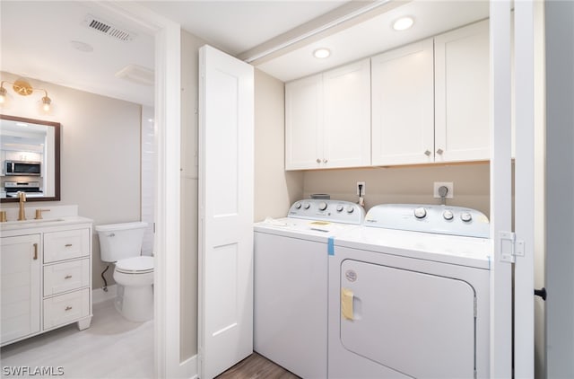 washroom with electric dryer hookup, cabinets, sink, and washer and dryer