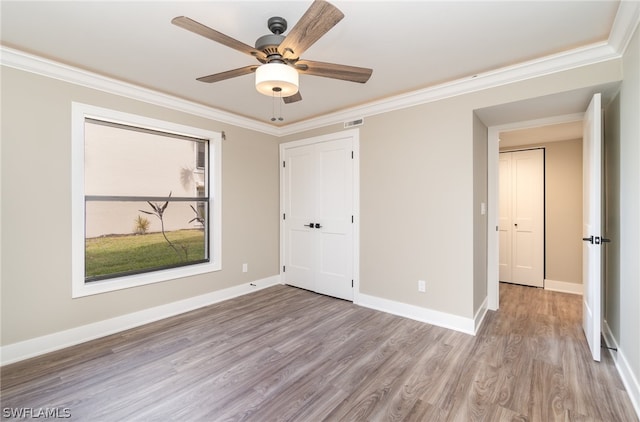 unfurnished bedroom with a closet, ceiling fan, crown molding, and hardwood / wood-style flooring