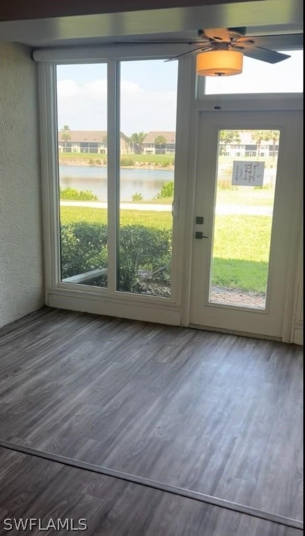 interior space featuring ceiling fan, a water view, and dark hardwood / wood-style floors