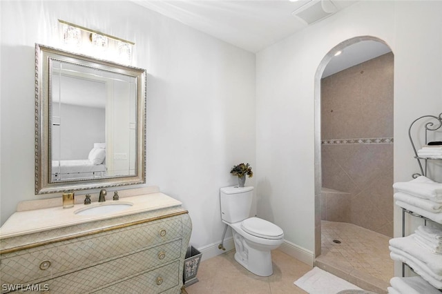 bathroom featuring tile floors, vanity, toilet, and tiled shower