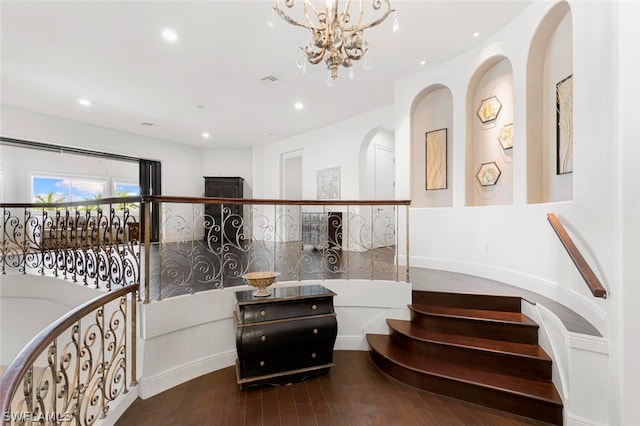 stairway featuring an inviting chandelier and dark hardwood / wood-style flooring