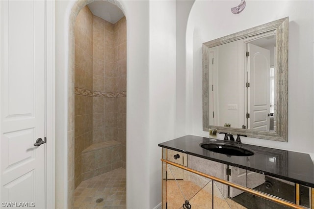 bathroom with tiled shower and vanity