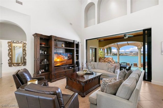 tiled living room featuring a water view and a towering ceiling