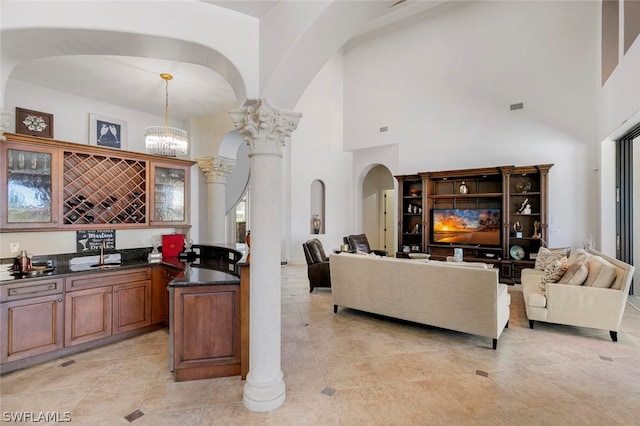 kitchen with a notable chandelier, decorative columns, light tile floors, and dark stone counters