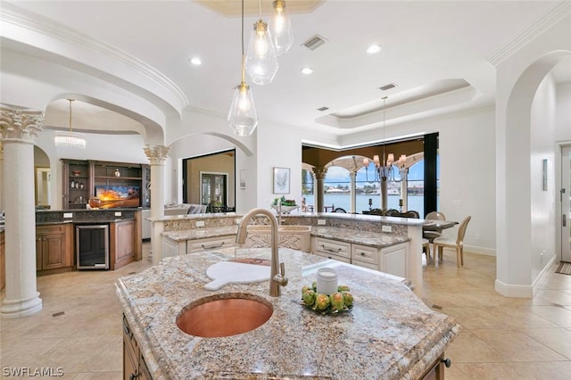 kitchen featuring a tray ceiling, hanging light fixtures, a spacious island, and light stone countertops