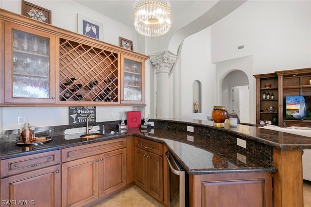 kitchen featuring hanging light fixtures, dark stone counters, sink, a notable chandelier, and light tile floors