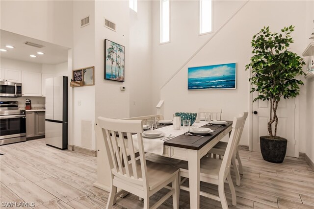 dining area featuring a high ceiling and light hardwood / wood-style flooring